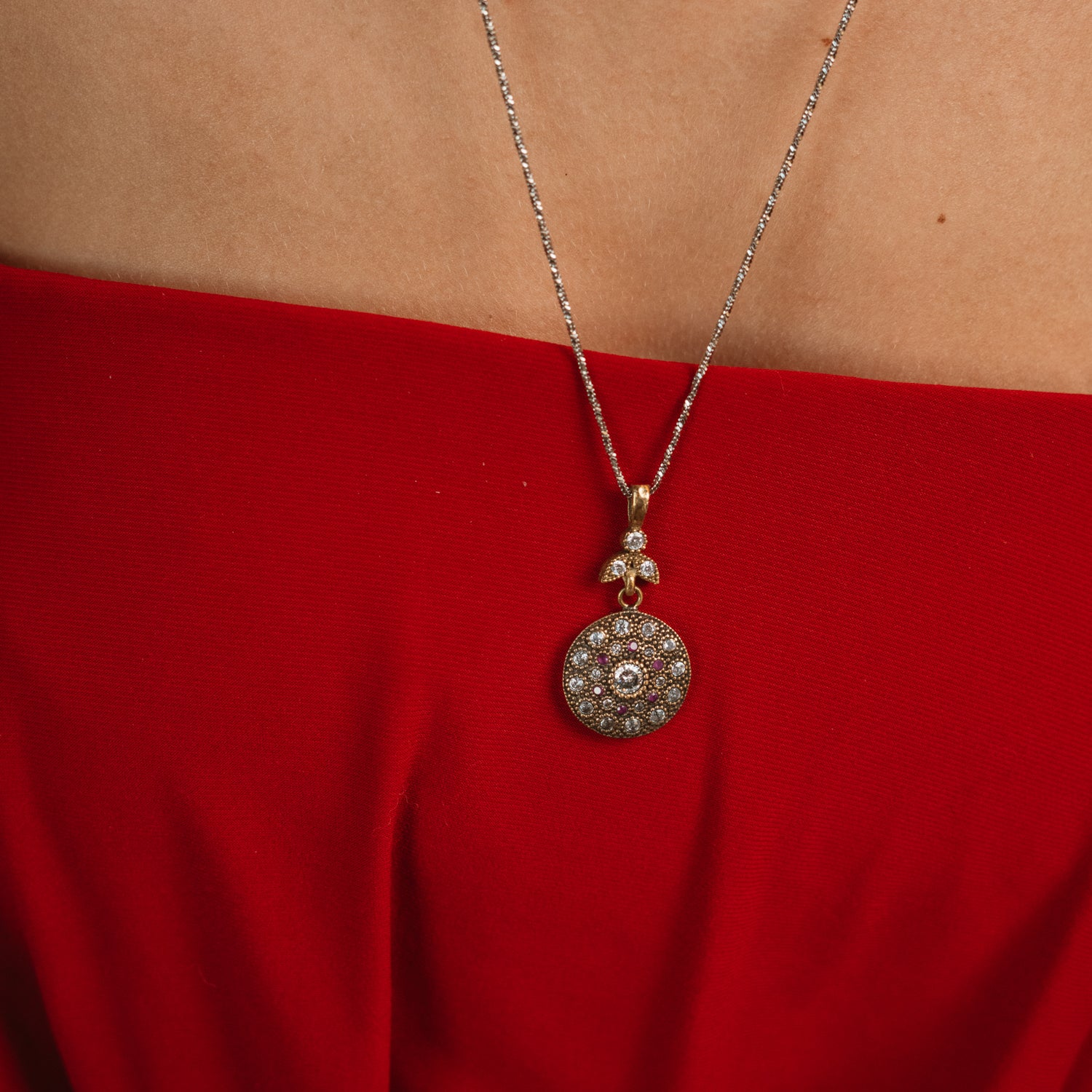 Model in a red dress wearing the Vintage Style Ruby &amp; Zirconia Gold Medallion Necklace, close view of the stone-set medallion