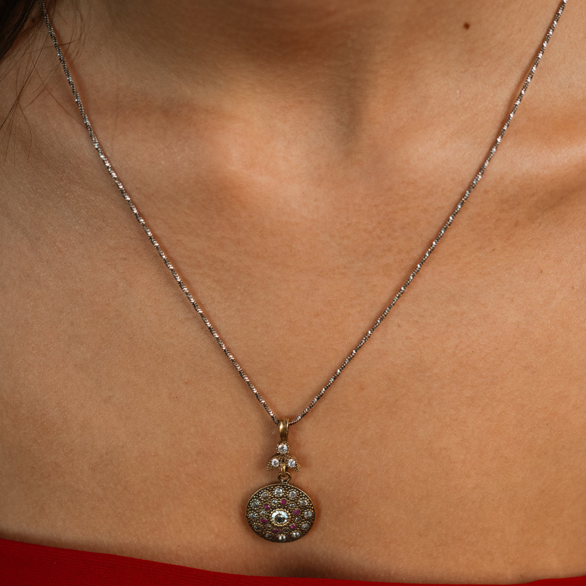 Vintage Style Ruby &amp; Zirconia Gold Medallion Necklace worn on the neckline, full view of the silver-tone chain and gold pendant