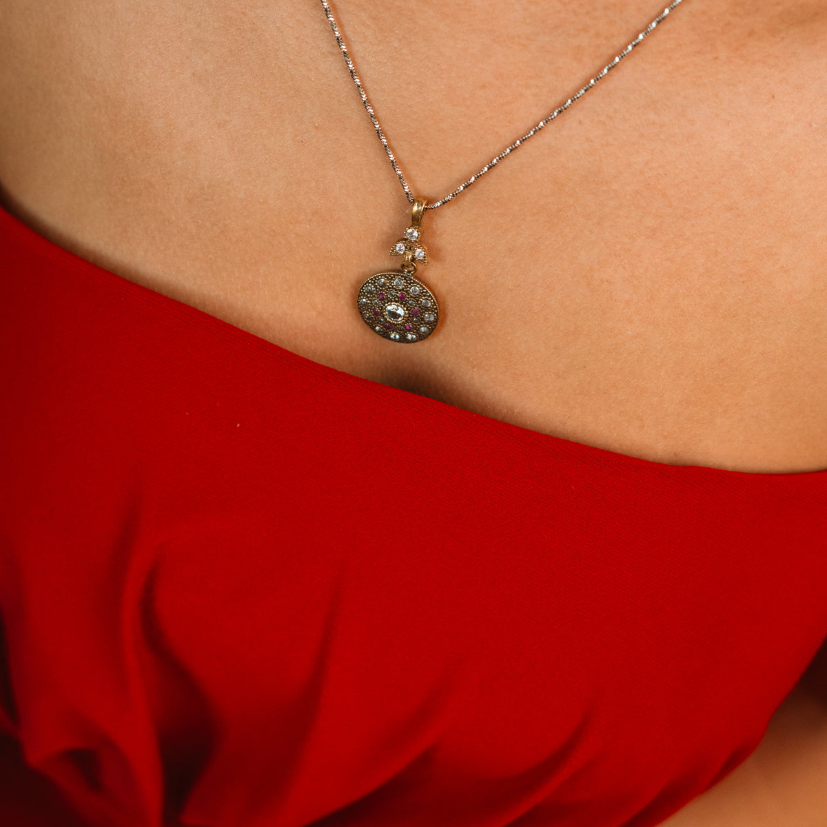 Vintage Style Ruby &amp; Zirconia Gold Medallion Necklace worn with a red top, medallion resting below the collarbone
