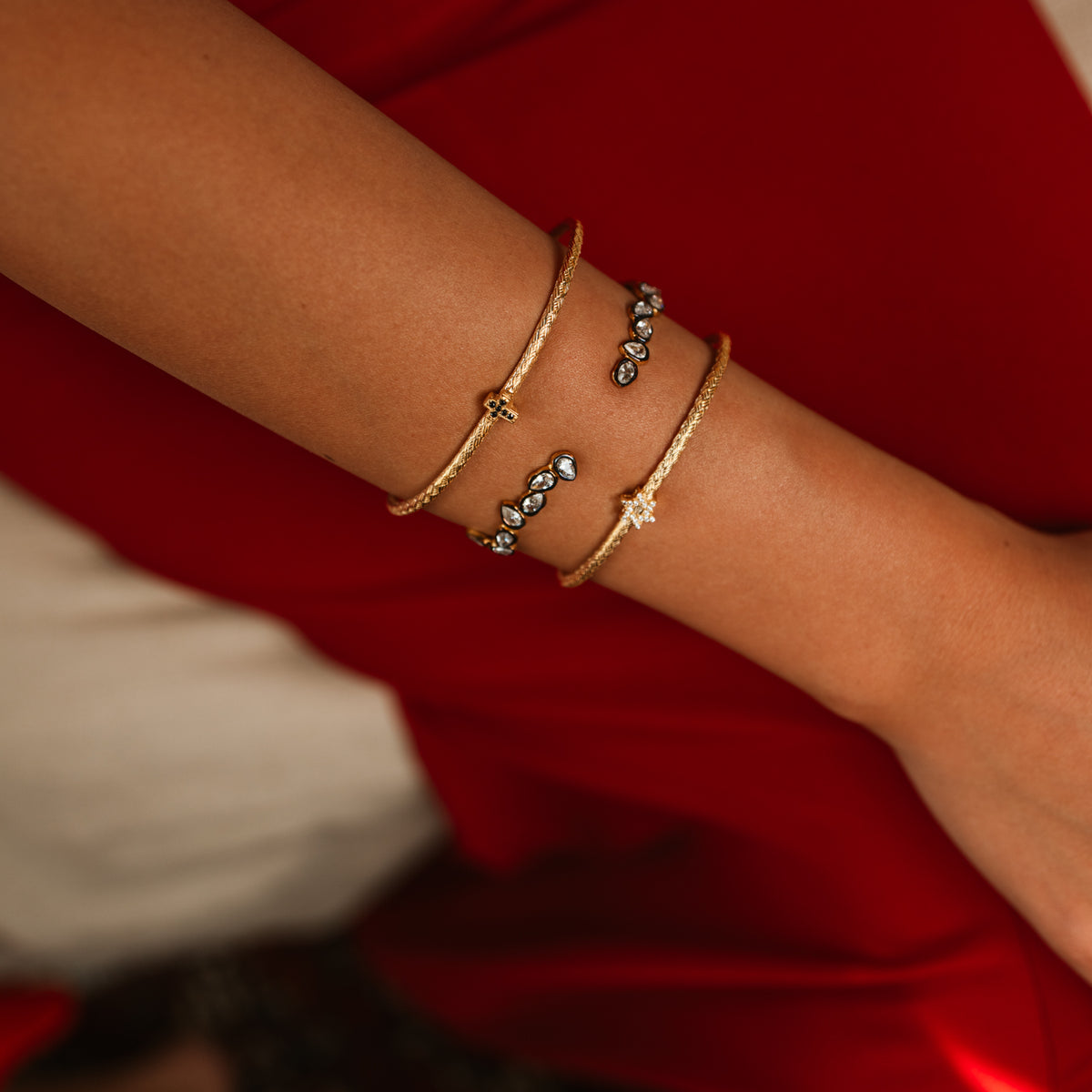 Close view of the teardrop two tone gold cuff worn in a stack of three gold cuffs