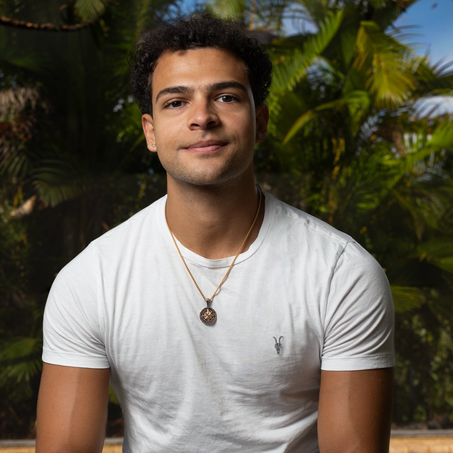 Man wearing gold compass pendant necklace with white t-shirt, mens jewelry styling by Ebru Jewelry