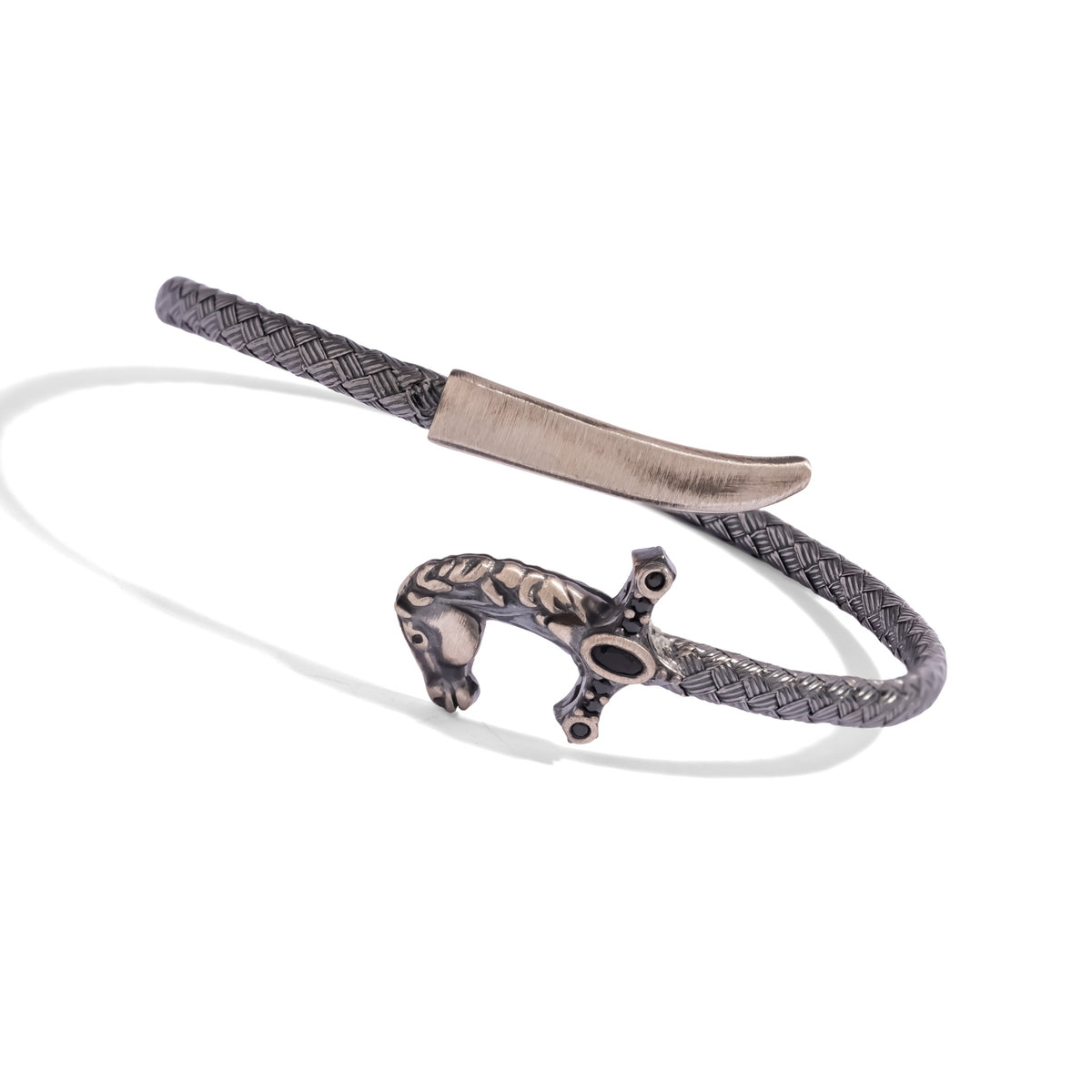 Angled view of the woven oxidized silver saber bracelet with the horse head hilt and the brushed silver blade tip overlapping