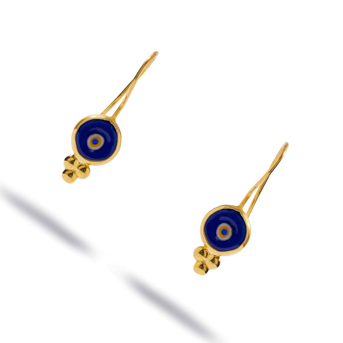 Watch Over Me blue evil eye gold drop earrings laid at an angle on white