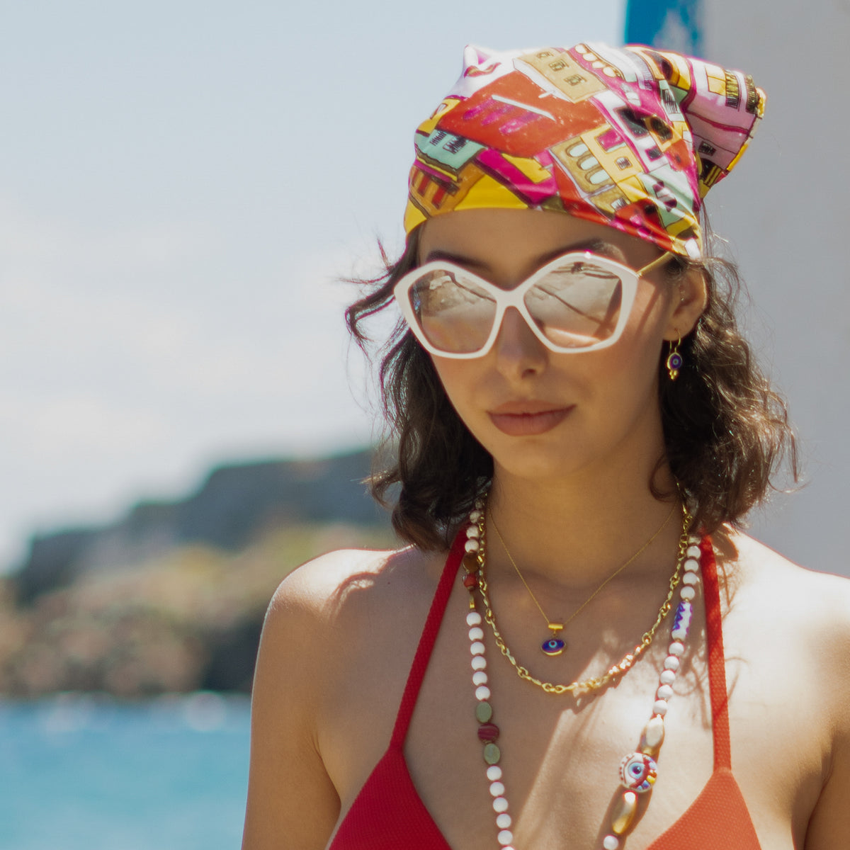 Model by the sea wearing the Watch Over Me Blue Evil Eye Gold Drop Earrings