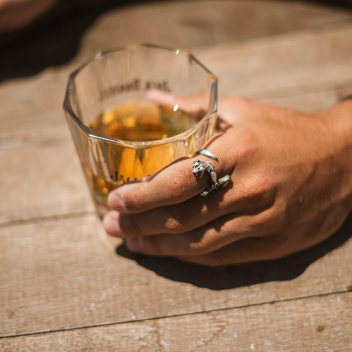 Oxidized sterling silver wolf sword ring on a man's hand in warm natural light