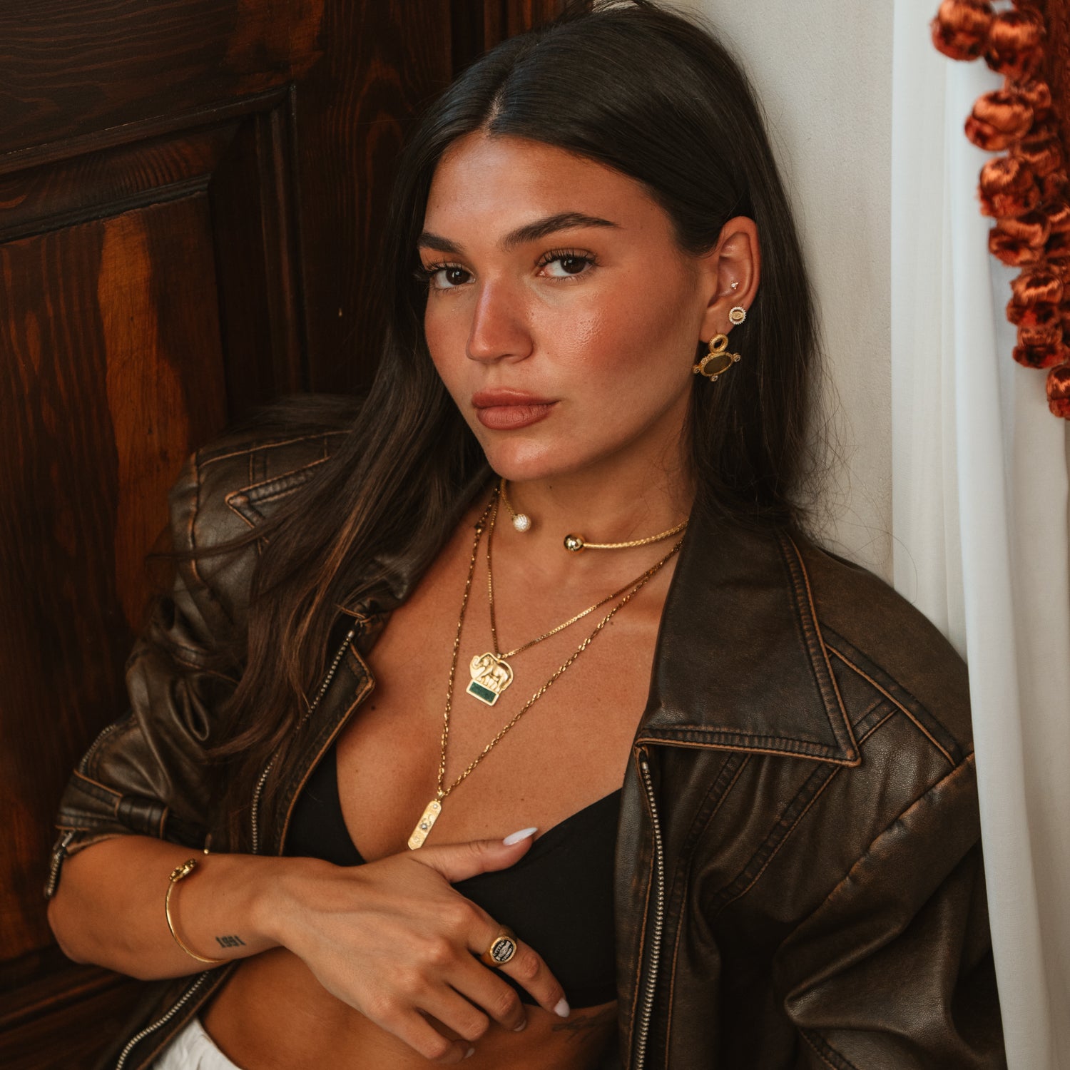 Model wearing woven gold vermeil pave sphere choker necklace layered with pendant necklaces under a leather jacket