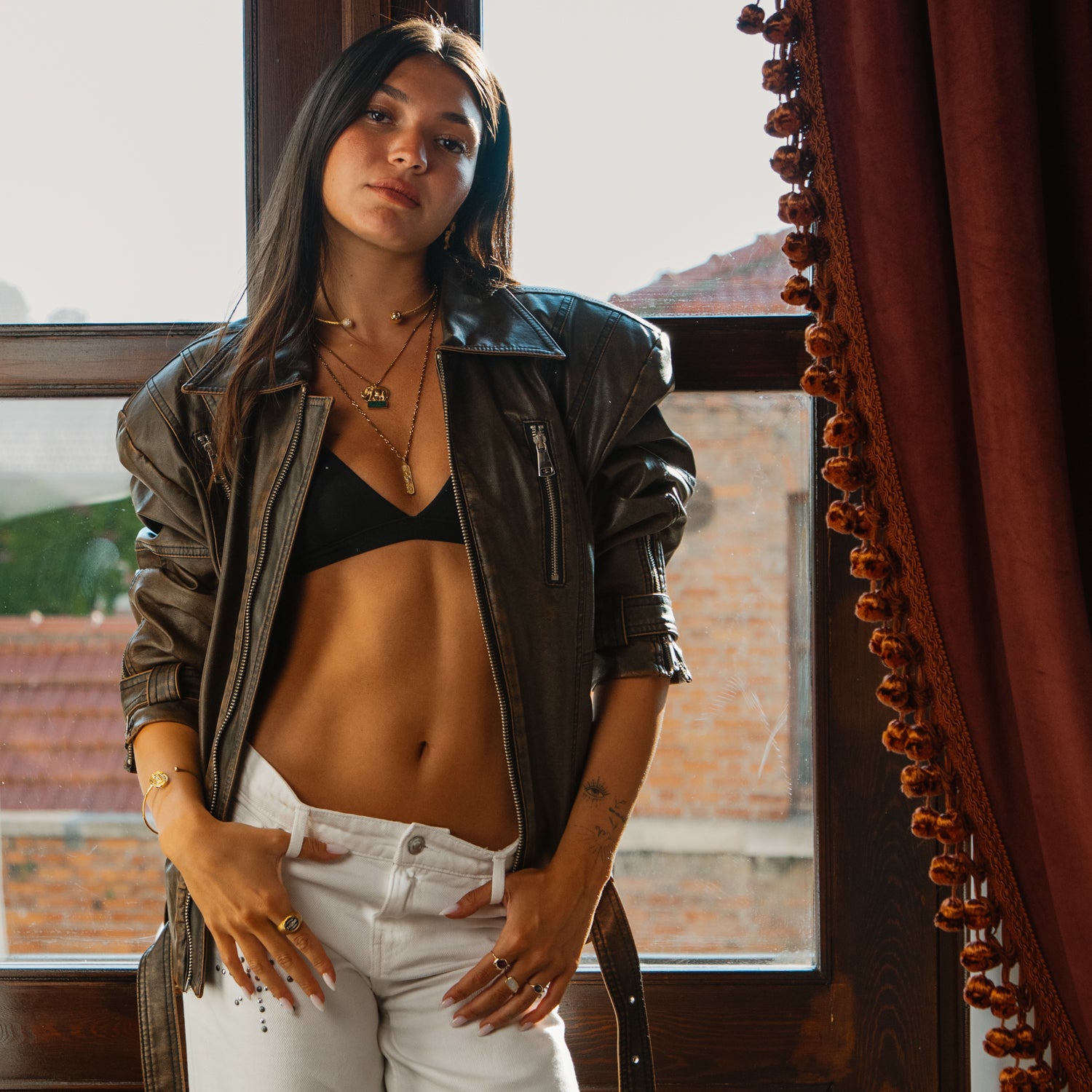 Woman in leather jacket wearing woven gold vermeil pave sphere choker necklace layered with pendant necklaces