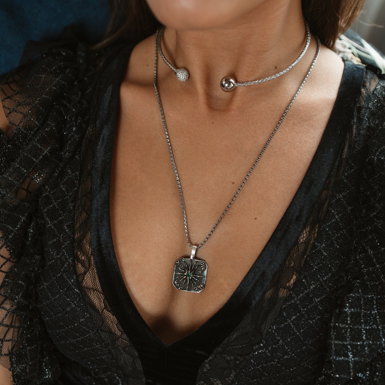 Detail of a woven sterling silver choker necklace styled with a silver clover pendant necklace