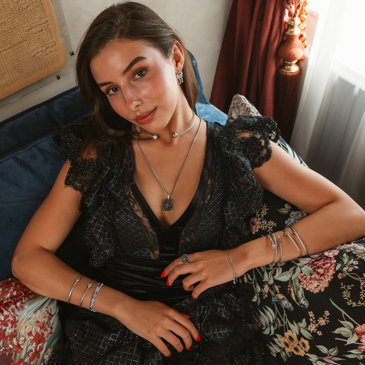 Model in black lace reclining on a sofa wearing the You Are The Sun Emerald Engraved Sterling Silver Pendant Necklace