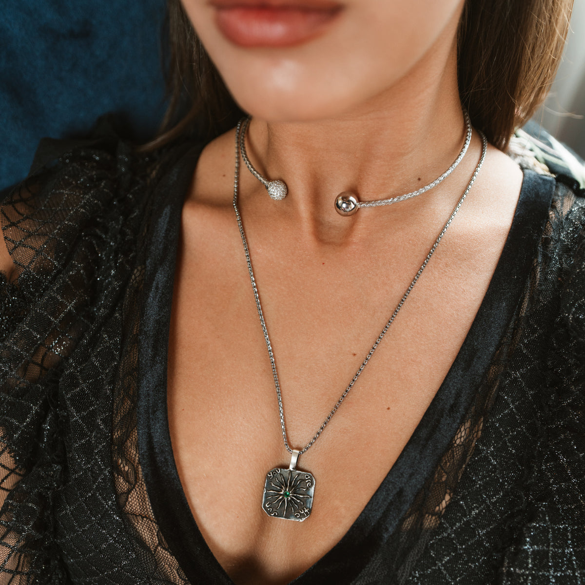 Close up of the You Are The Sun silver pendant worn on a long chain below a silver collar necklace