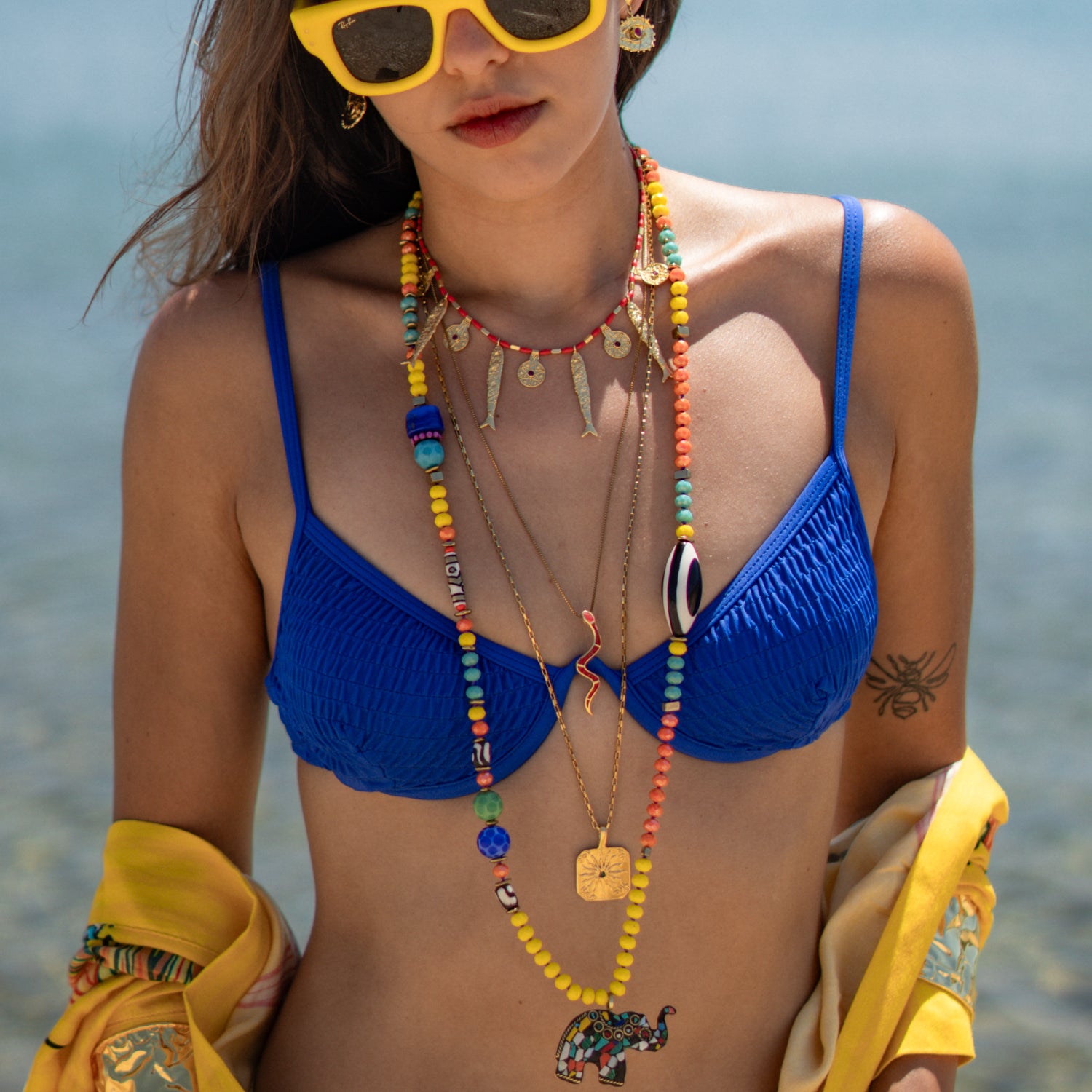 Layered beaded necklaces with the gold engraved sun pendant necklace at the longest length