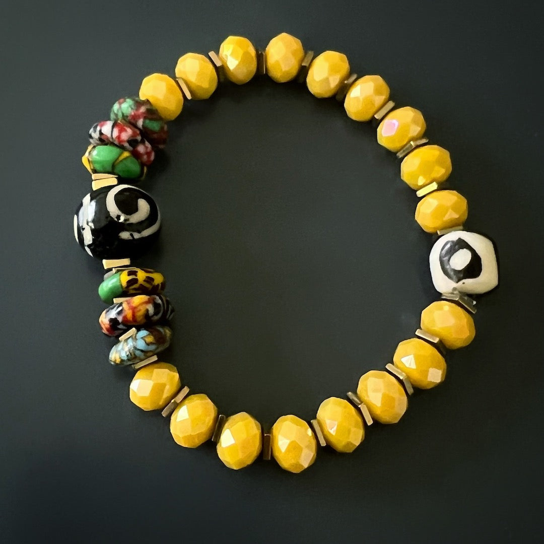 A close-up image of the African Yellow Women Bracelet, highlighting the intricate details of the colorful African beads and the eye-catching spiral and eye Nepal beads.