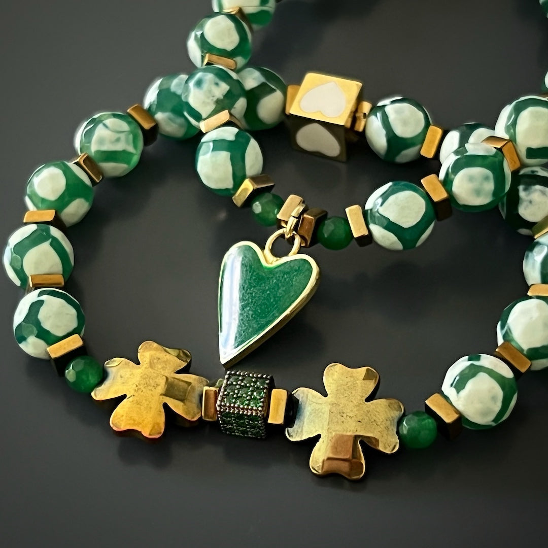 Adorned with Nepal Agate beads and gold hematite clover leaf beads, this bracelet set captivates with its 18K gold-plated green enamel heart charm and white enamel heart bead. The intricate design and thoughtful craftsmanship make it a truly enchanting piece.