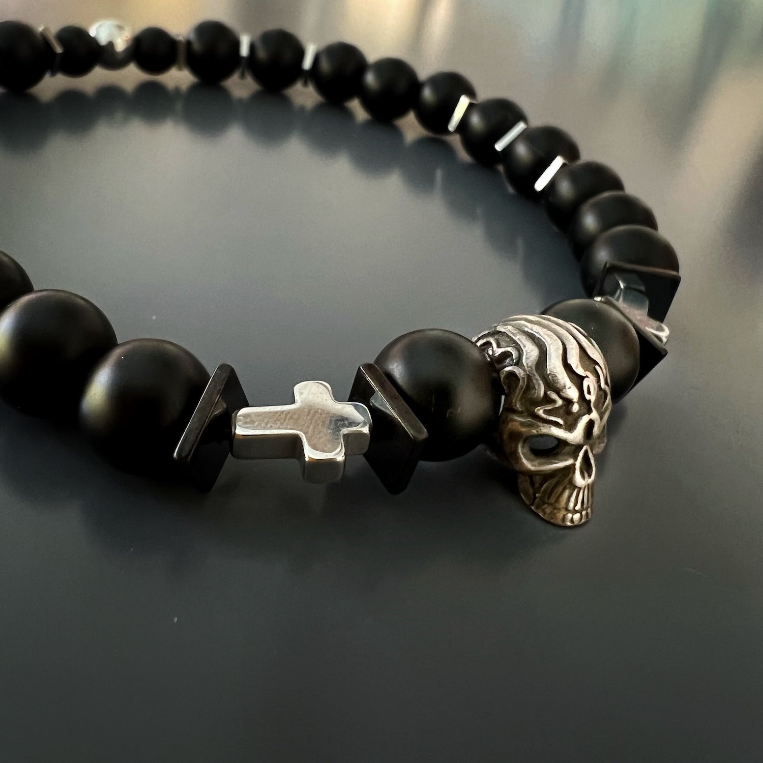 The combination of black onyx stones, sterling silver skull bead, and silver hematite cross beads creates a stylish and meaningful accessory that inspires courage and resilience.