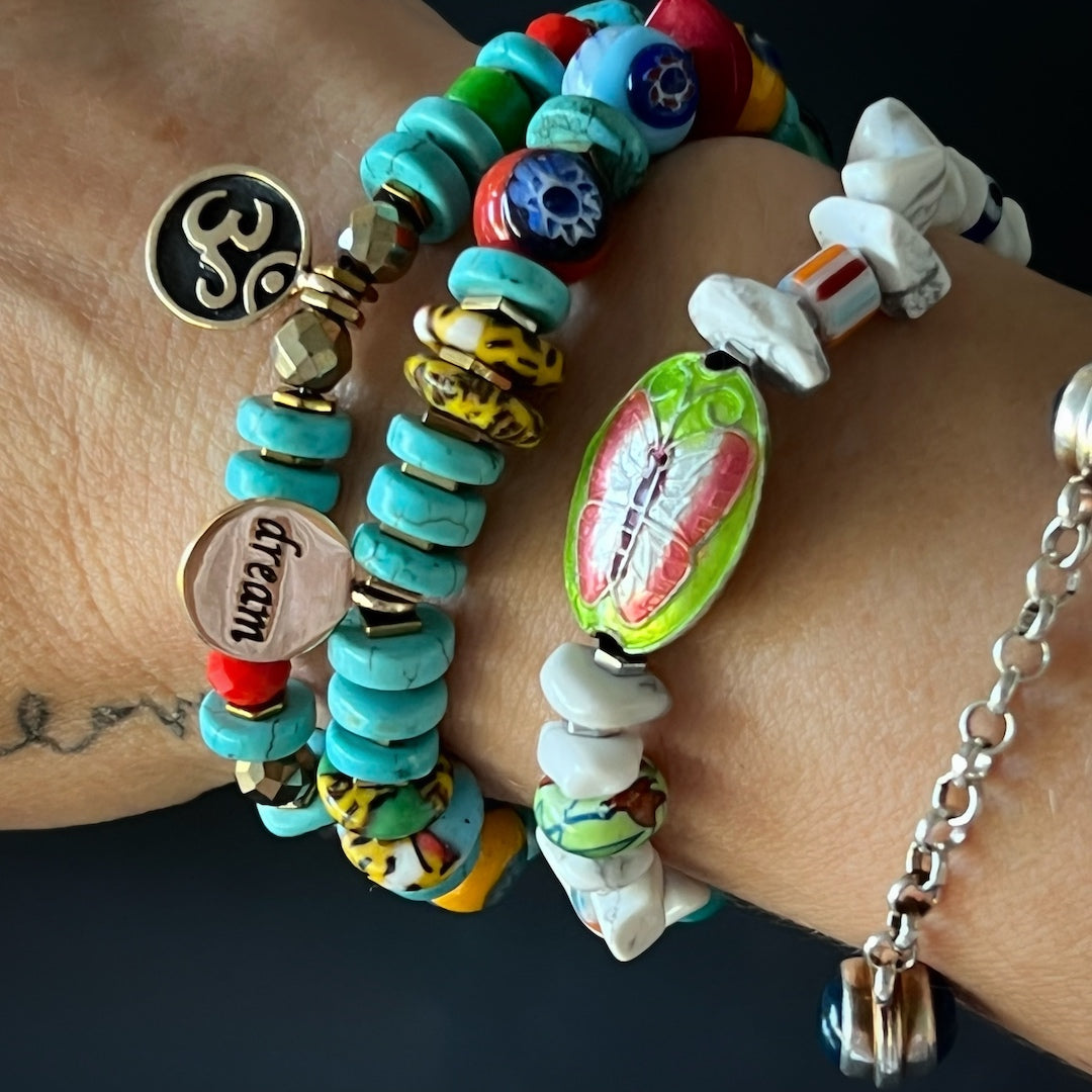 A close-up view of a hand model wearing the Cycle of Life Butterfly Bracelet. The bracelet&#39;s combination of howlite beads, African beads, and the butterfly charm creates a captivating and symbolic accessory.