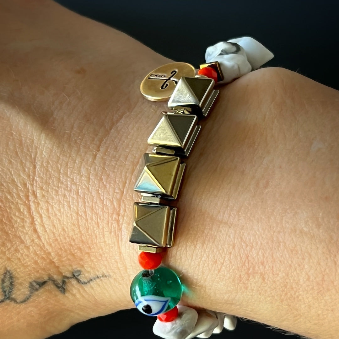 A hand model wearing the Cycle of Life Evil Eye Bracelet. The bracelet beautifully adorns the wrist, showcasing the howlite beads, African beads, and the bronze heal mantra charm.
