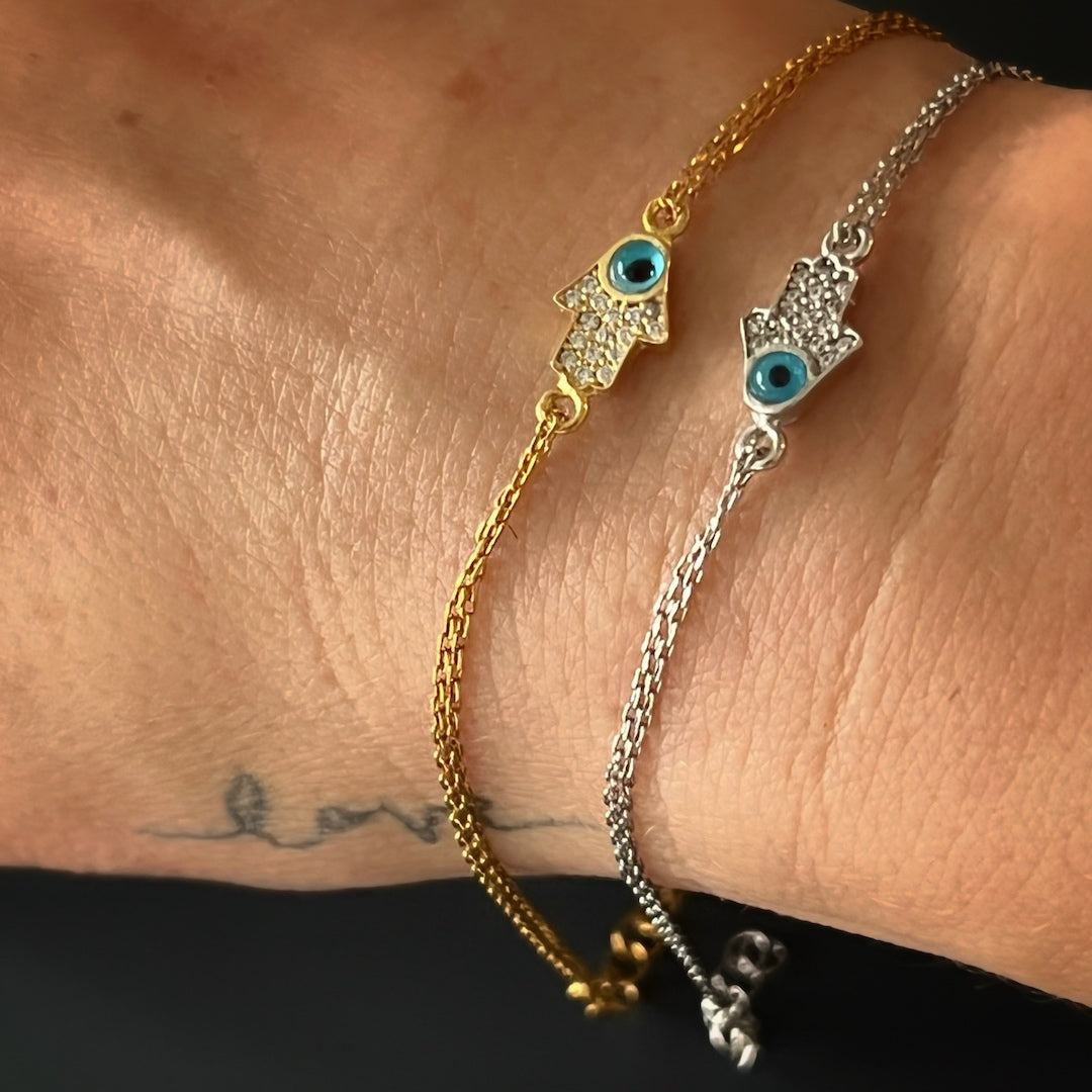 The Dainty Evil Eye Hamsa Bracelet styled on a hand, adding a touch of protection and symbolism to the overall look.