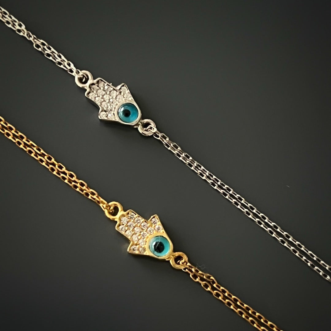 Dainty Evil Eye Hamsa Bracelet in sterling silver featuring a small hamsa with an evil eye charm. The bracelet has a simple and elegant design, perfect for everyday wear.