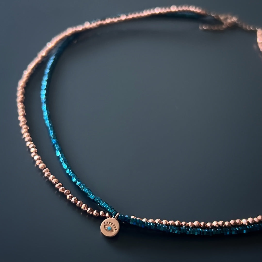 An image displaying the Dainty Hematite Evil Eye Choker Necklace, emphasizing its elegance and the symbolic protection associated with the evil eye charm.