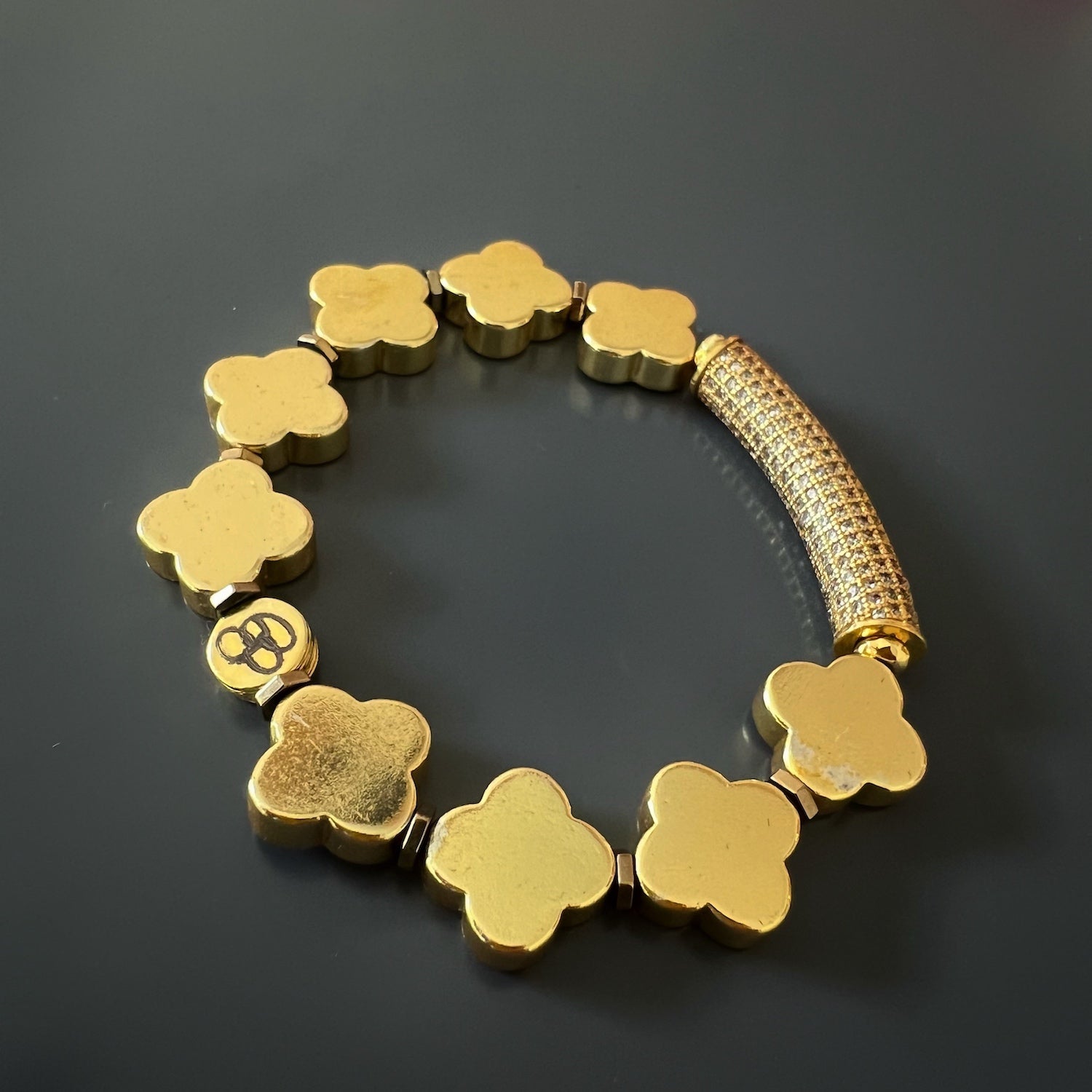 The Diamond and Gold Clover Bracelet laid flat on a surface, displaying its exquisite craftsmanship and the charming arrangement of the gold clover beads.