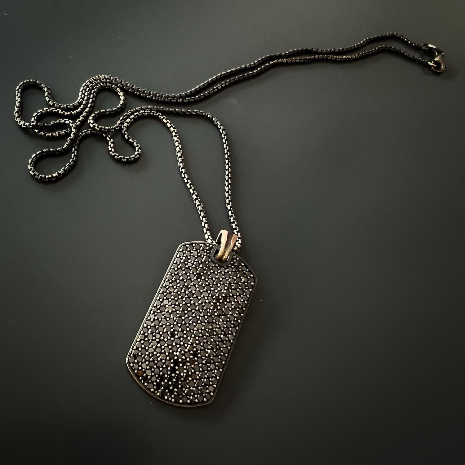 Close-up of the pendant's black diamond pave, capturing the intricate details and luxurious sparkle of the necklace.