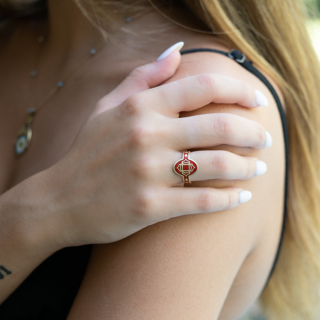 Hand model showcasing the Enamel Chakra Ring - A captivating piece with a red enamel design on a recycled gold band, handcrafted with love and care for a meaningful and stylish accessory.