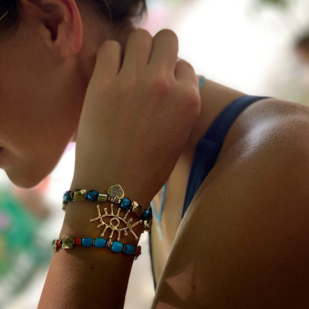 A hand model wearing the Evil Eye Dream Bracelet, showcasing its beautiful turquoise beads and symbolic charms.