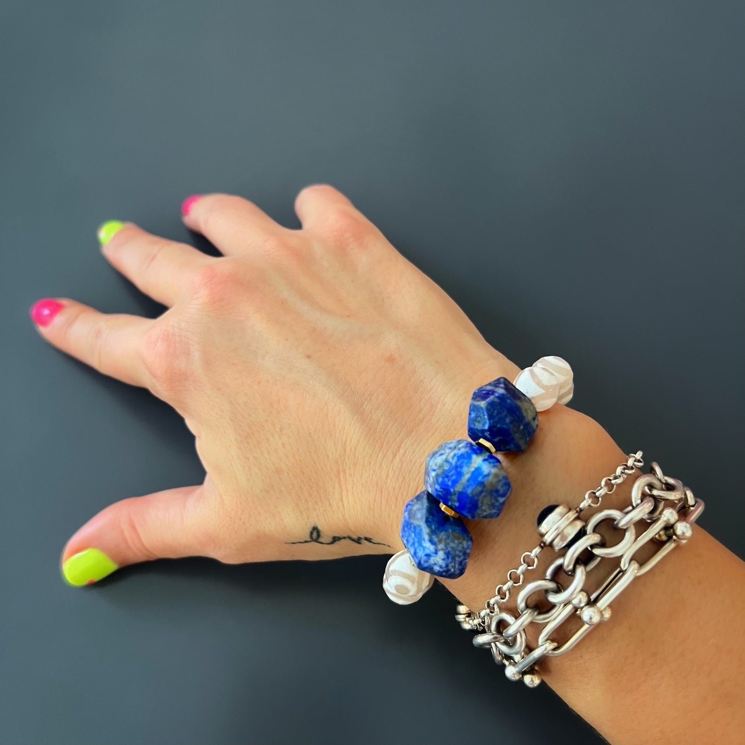 Eye of Love Lapis Lazuli Bracelet on Hand Model - Unique and eye-catching, featuring Lapis Lazuli, White Nepal agate, and a Gold plated blue enamel heart.