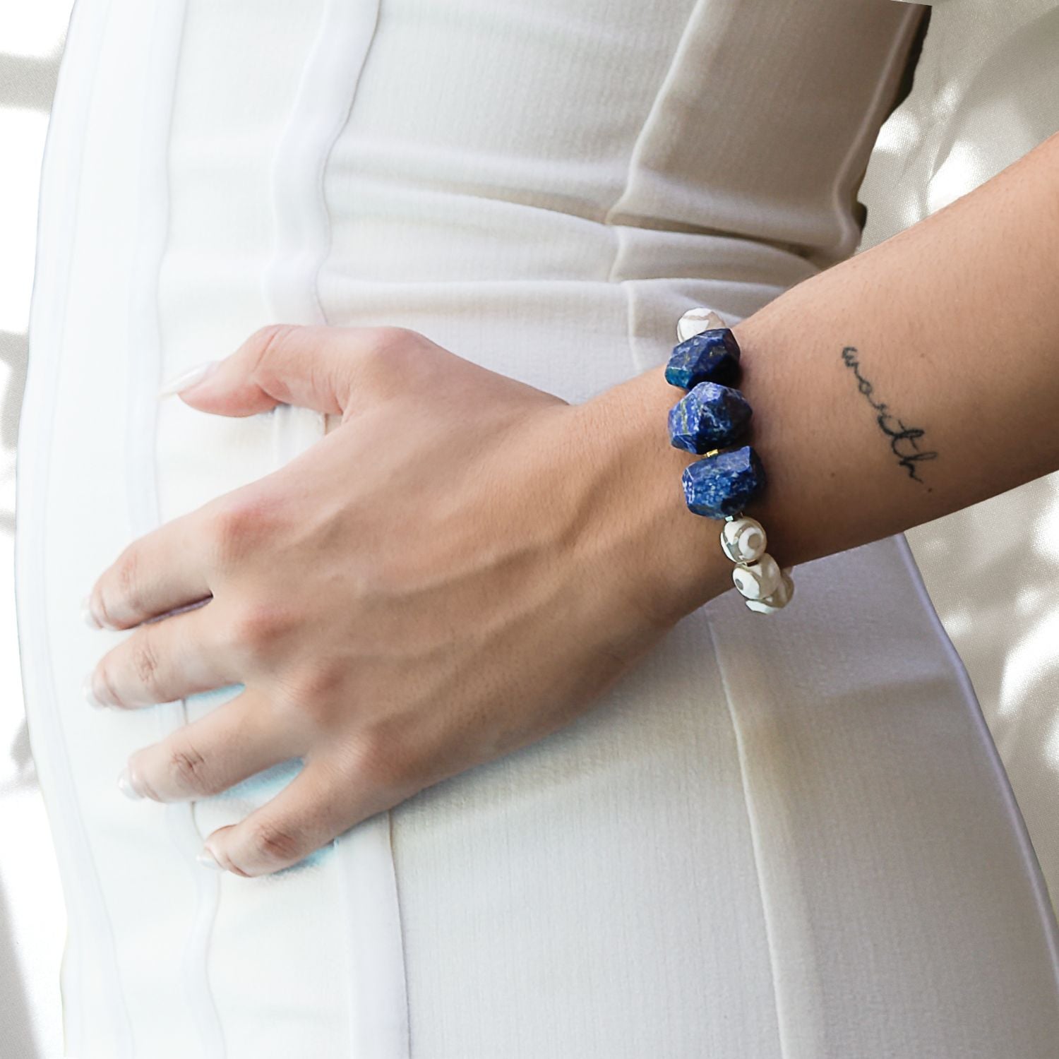Hand model wearing Eye of Love Lapis Lazuli Bracelet - Handcrafted with Lapis Lazuli, White Nepal agate, and a Gold plated blue enamel heart bead.