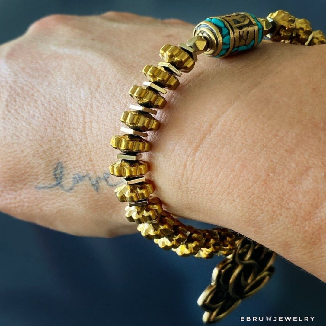 Stylish hand model wearing Flower Of Life Bracelet - Meticulously crafted accessory featuring a Lotus Flower charm, Buddha quote message charm, and gold color hematite beads, perfect for spiritual inspiration.