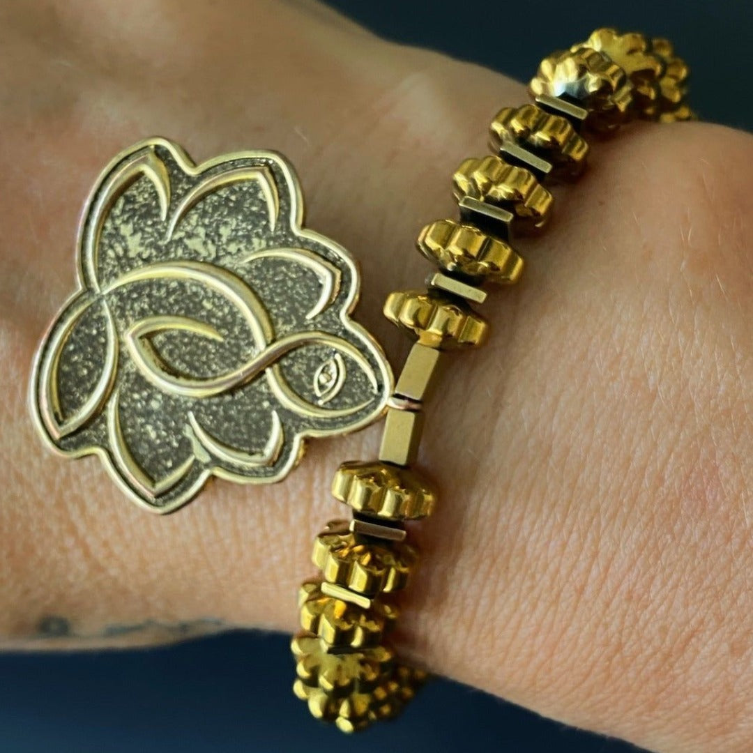 Hand model wearing Flower Of Life Bracelet - Handcrafted accessory with gold color hematite beads, Lotus Flower charm, and Om Mani Padme Hum mantra bead, radiating positive energy and style.