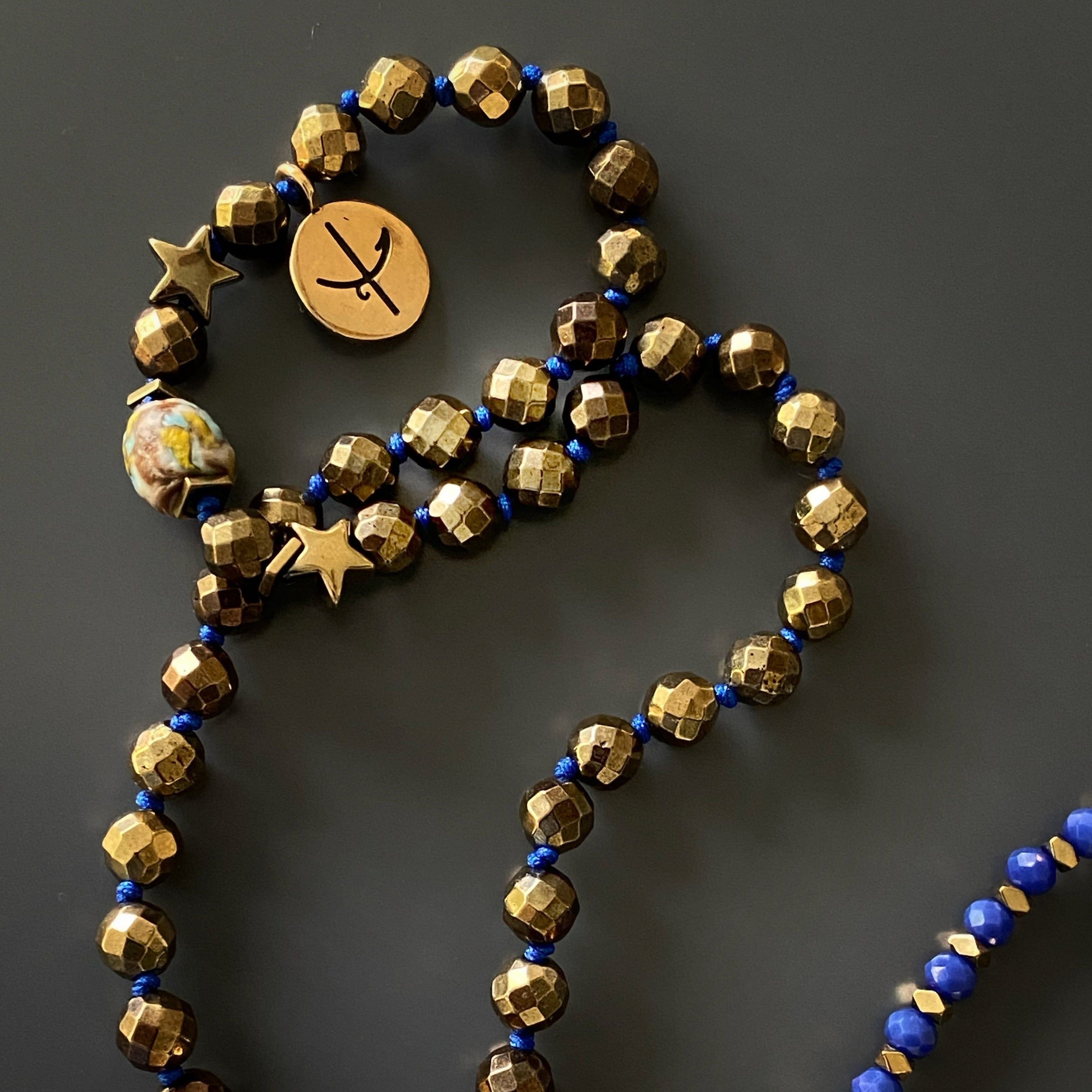 Handcrafted Isis Necklace - Elegant necklace adorned with blue crystal beads, gold hematite stones, and a handcrafted bronze pendant of the Egyptian Goddess Isis, representing healing and empowerment.