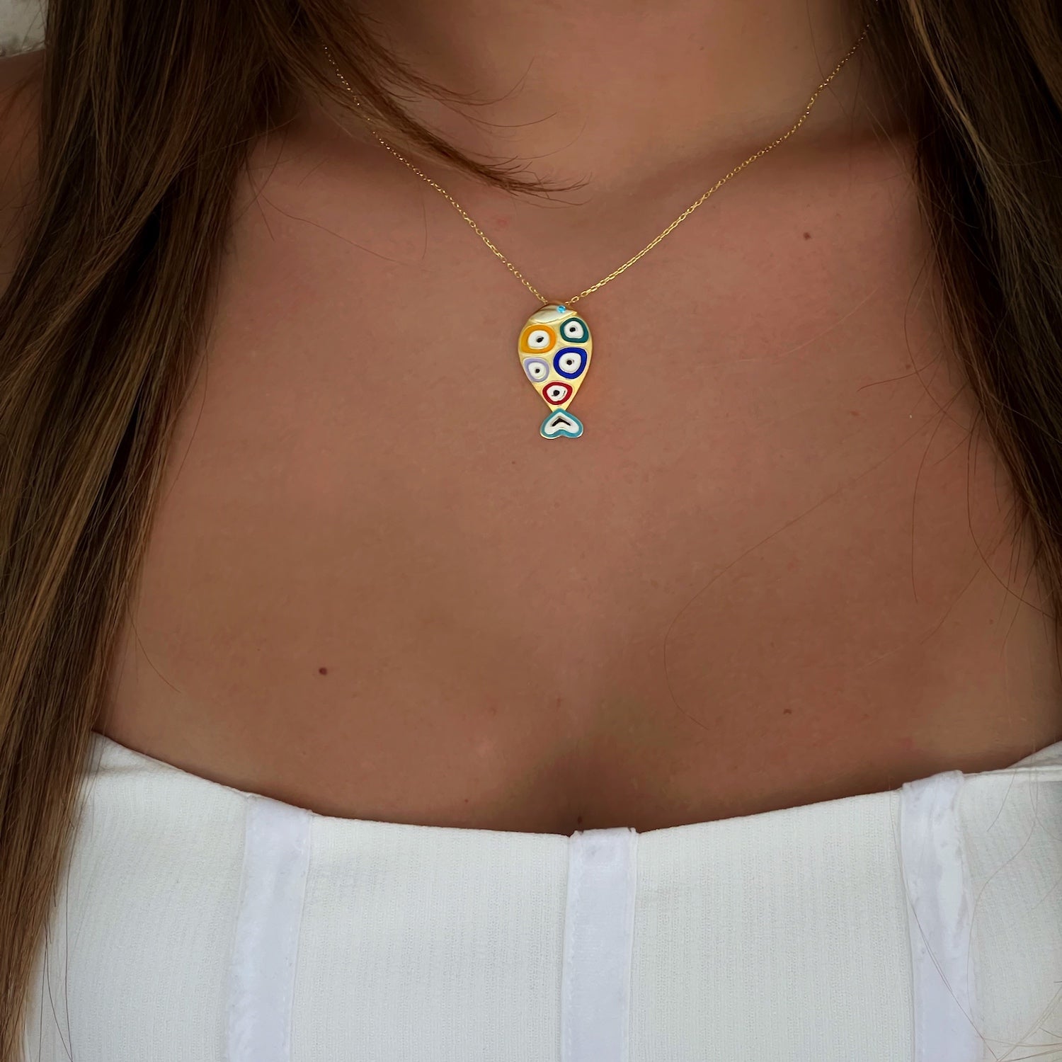 Close-up image of the Gold and Blue Evil Eye Fish Necklace, highlighting the intricate fish pendant with blue enamel and the surrounding evil eye designs.
