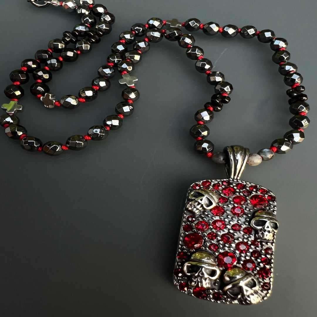 Edgy necklace showcasing hematite stone beads and a stainless steel skull pendant adorned with red crystals