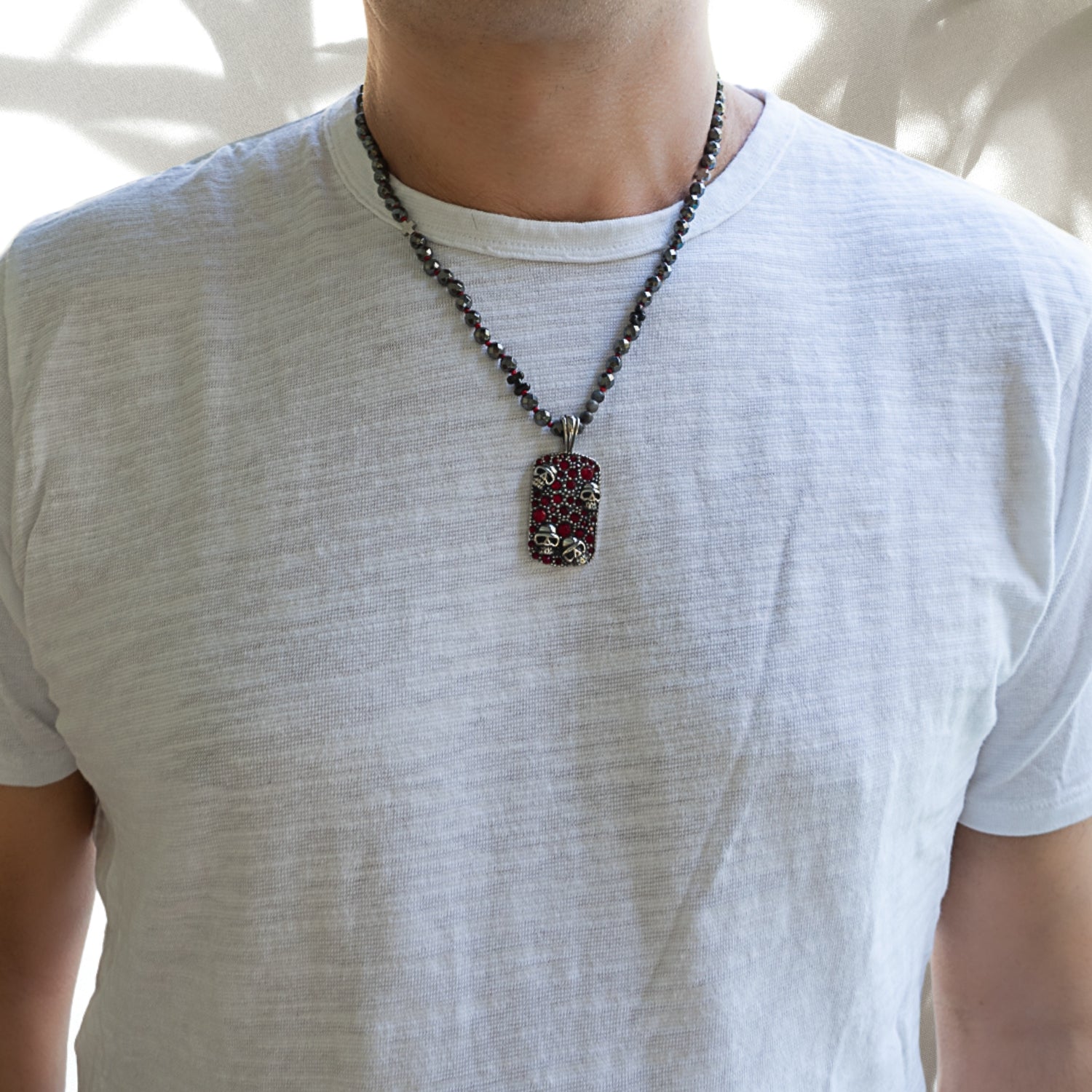 Model wearing the Gothic Red Skull Necklace, featuring black faceted hematite beads and a stainless steel skull pendant with red zircon crystals