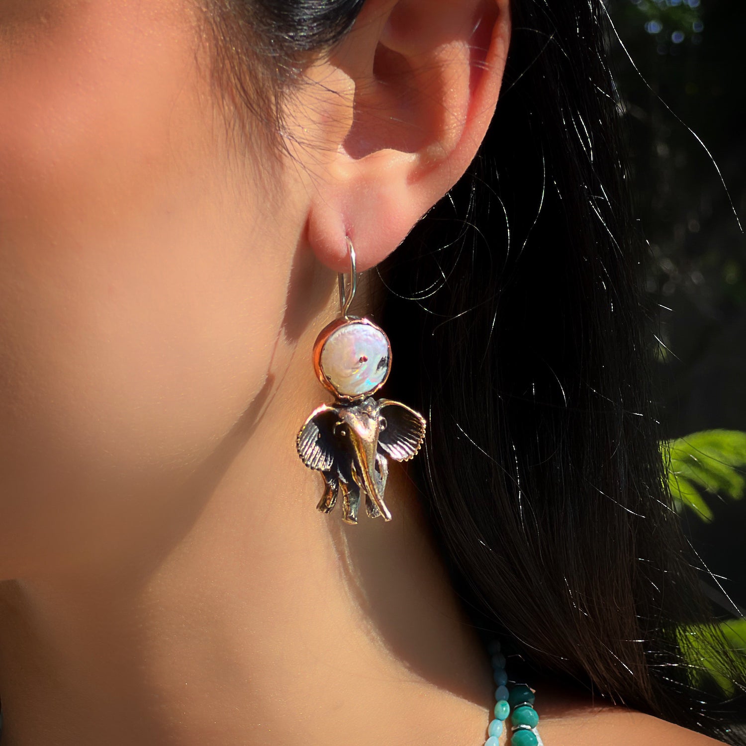 An image of a model wearing the Handmade Unique Spirit Elephant Earrings, demonstrating how they can effortlessly elevate any look with their whimsical design and eye-catching pearl gemstone accent.