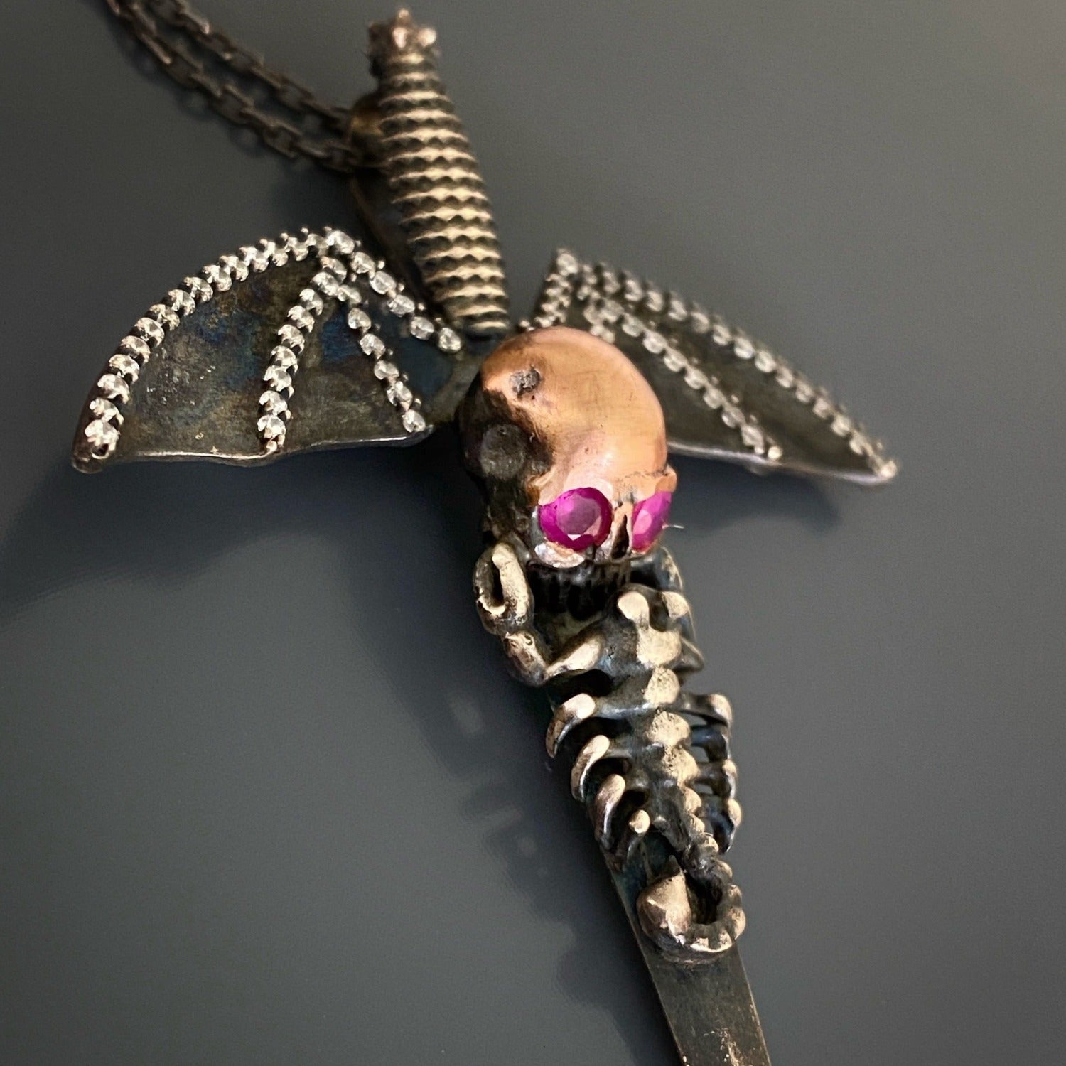Silver Skull Pendant Necklace with Wings - Unleash your inner rebel with this handcrafted necklace featuring a silver skull pendant, embellished with bat wings, and accentuated by the fiery brilliance of ruby eyes.