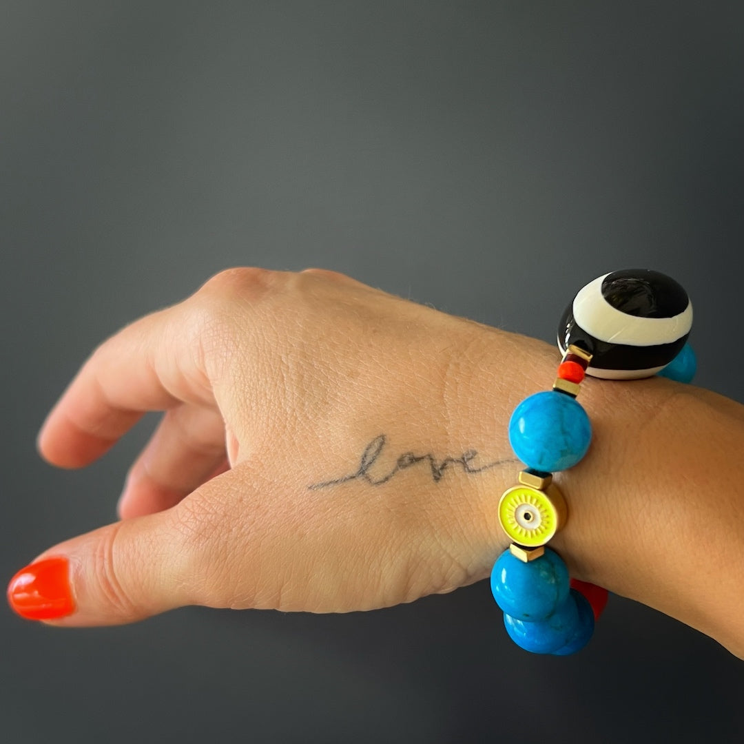 An image of a hand model wearing the Happiness Turquoise Eye Bracelet, showing how it adds a pop of color and style to the wrist, creating a playful and vibrant accessory.
