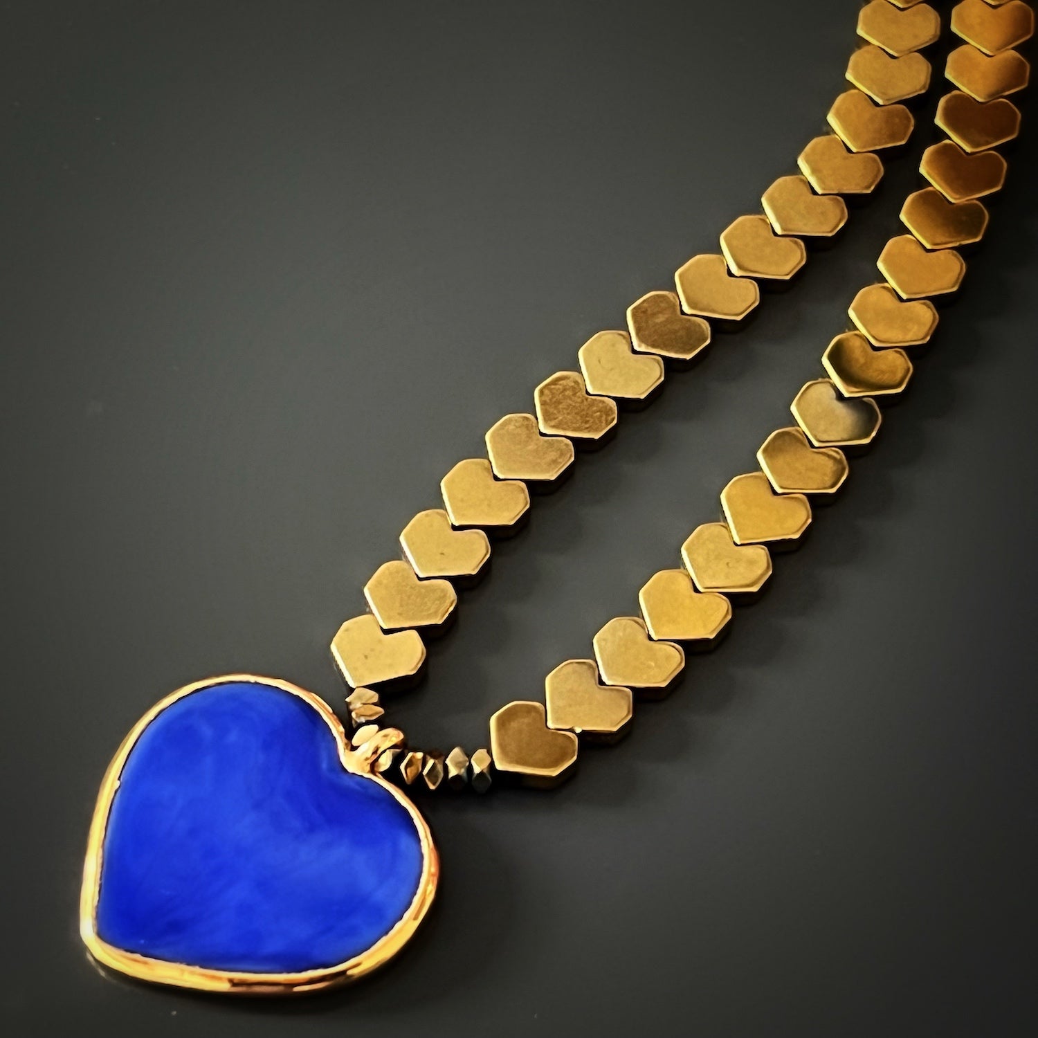 A close-up shot of the vibrant 18K gold plated blue heart ceramic pendant of the Happy Blue Heart Necklace, showcasing its intricate details and the captivating shade of blue, making it a standout feature of the necklace.