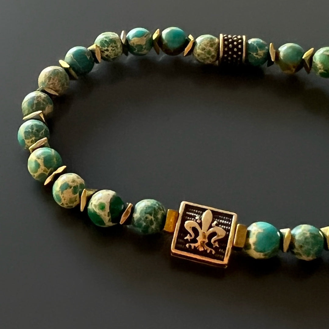A unique men&#39;s bracelet with Blue Variscite stone beads and a Bronze gold-plated Fleur de lis accent bead, representing tranquility and balance.