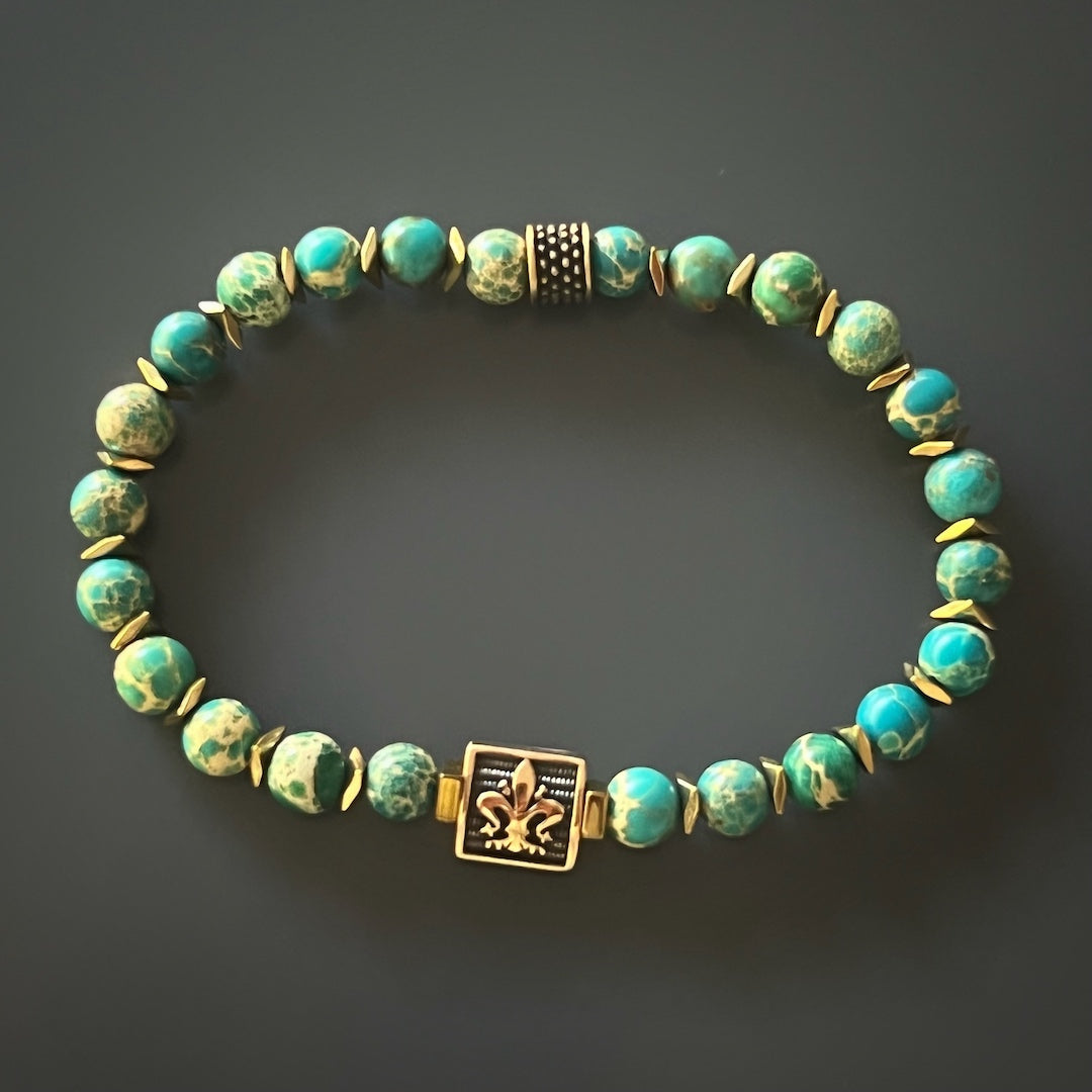 A handmade bracelet with Blue Variscite stone beads and a Bronze gold-plated Fleur de lis accent bead.