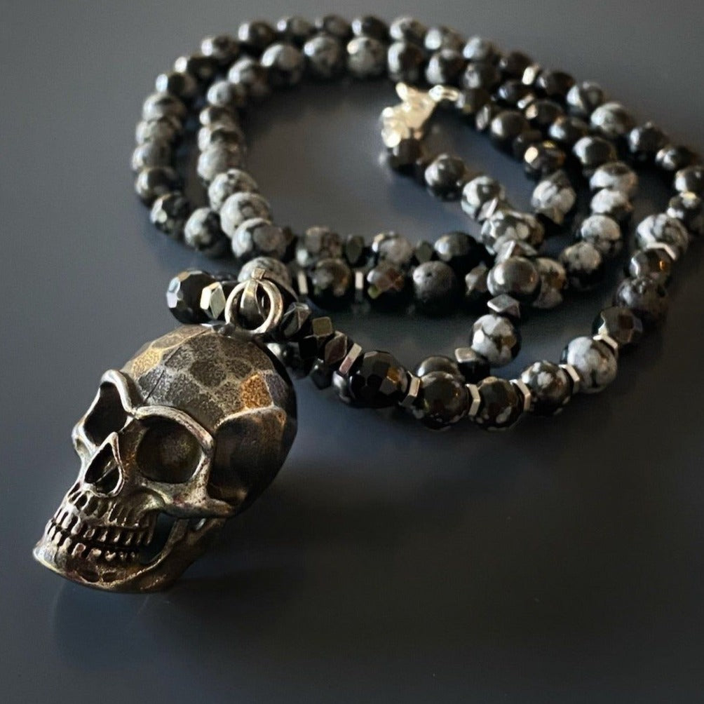 A unique necklace with Hematite and Obsidian Snowflake stone beads, accentuated by a handmade Steel Skull Pendant.