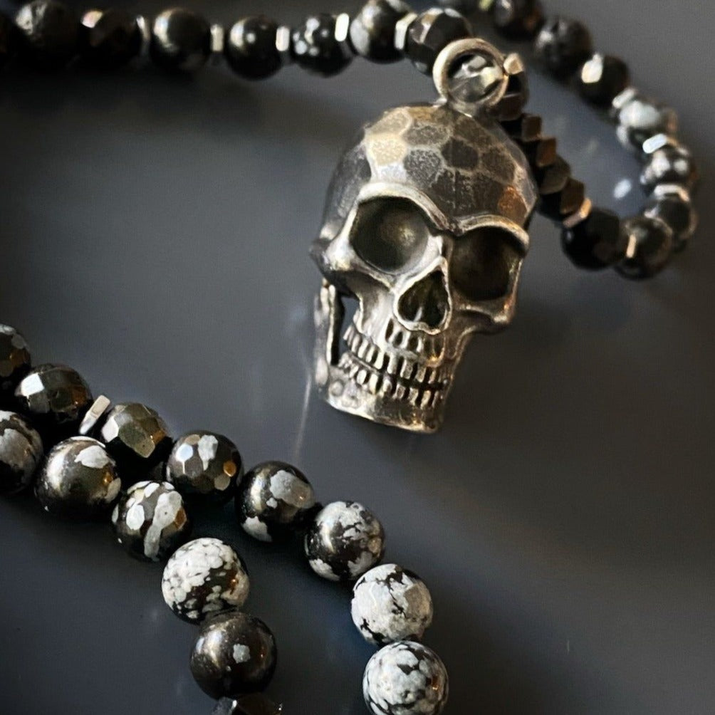 A captivating necklace with Hematite and Obsidian Snowflake stone beads, adorned with a handmade Steel Skull Pendant.