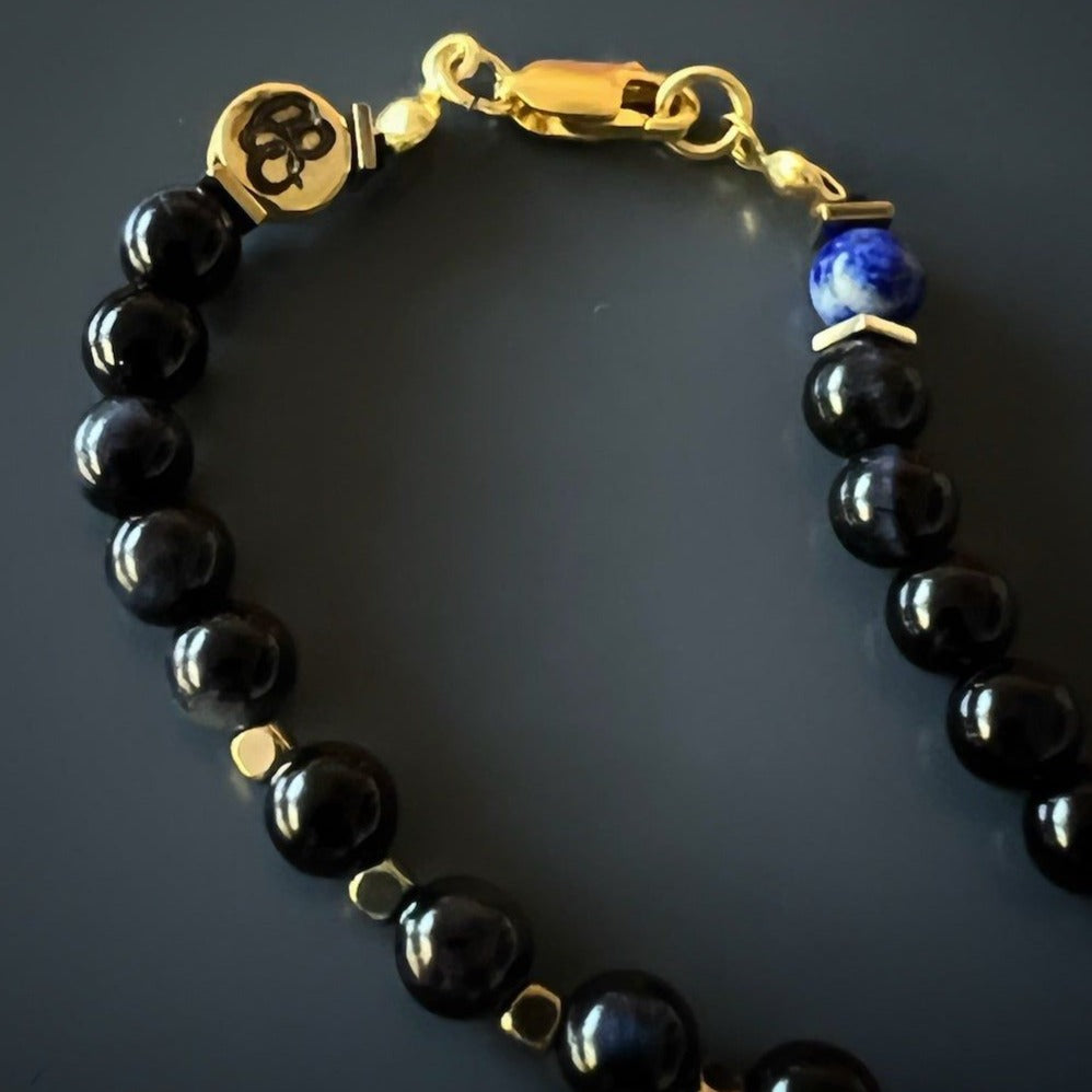 the Kolovrat Sun Cross Necklace, highlighting the smooth texture of the tiger&#39;s eye and lapis lazuli stone beads, and the craftsmanship of the gold-plated sun cross pendant.