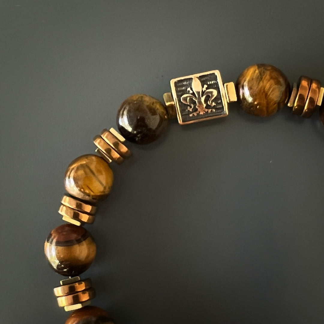 Embrace your strength and confidence with the Lion Men Bracelet, featuring Tiger&#39;s eye stone beads and a striking bronze Fleur de li bead.