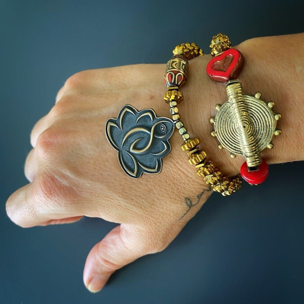 Discover the beauty and spirituality of the Lotus Flower Mantra Bracelet, featuring a Lotus Flower charm and a powerful Om Mani Padme Hum mantra bead, worn by a hand model.