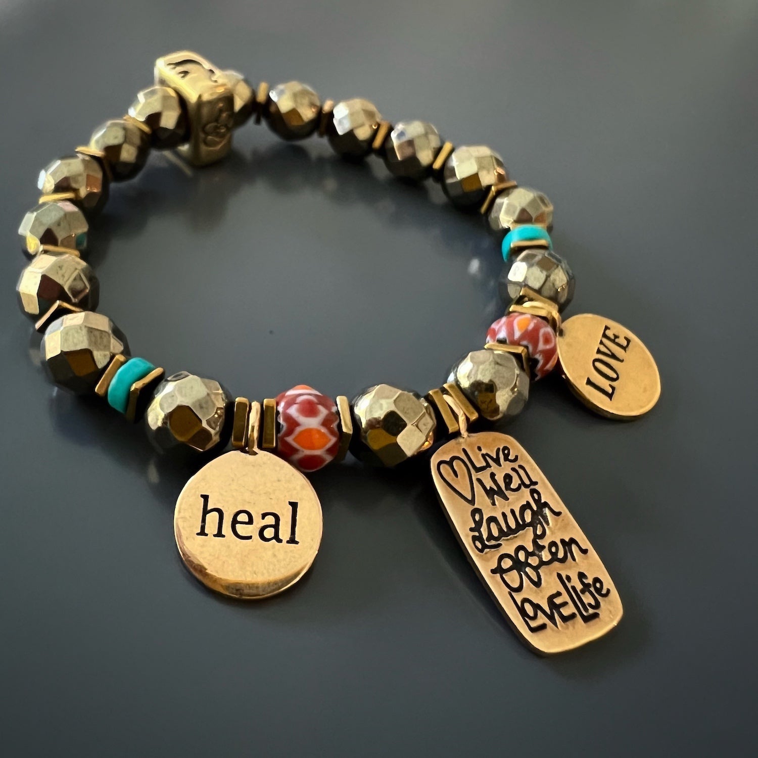 Feel the positive energy of the "Love Your Life" Bracelet, adorned with gold hematite beads and bronze charms with empowering messages.