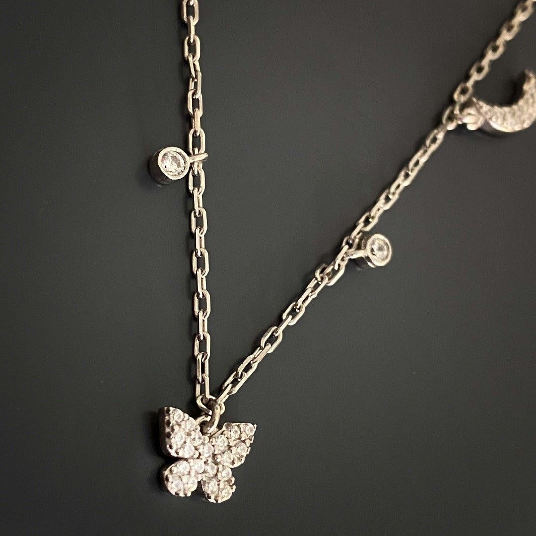 Elevate your style with the Lucky Symbols Necklace, showcasing a combination of lucky symbols, including evil eye, moon, butterfly, thunder, star, and rainbow, a stunning accessory handcrafted with 925 sterling silver.