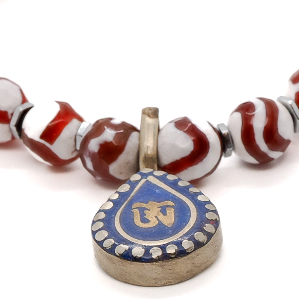 Experience the grounding and mystic allure of the Maya Bracelet, showcasing Striped Nepal Agate, Silver Hematite spacers, and a stunning Om Mantra charm with Lapis Lazuli.
