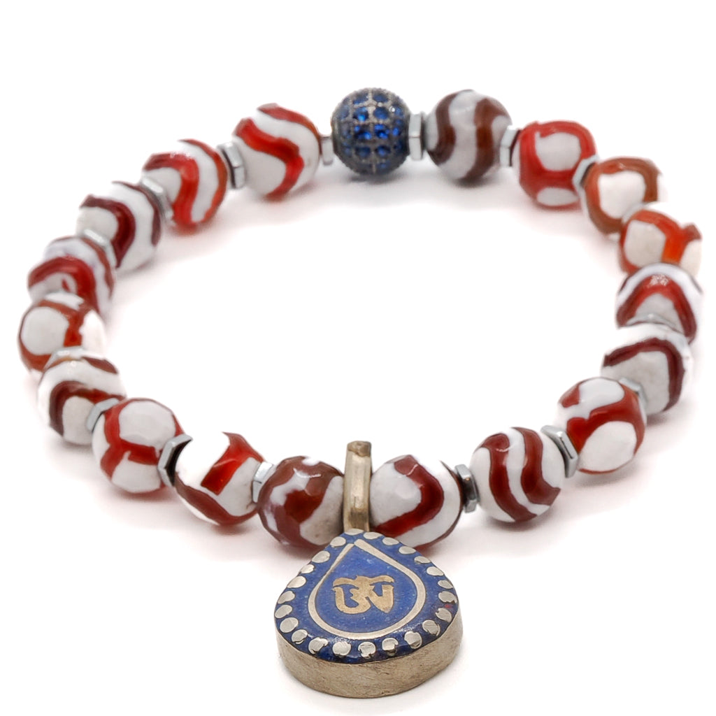Unleash your inner spirituality with the Maya Bracelet, adorned with Striped Nepal Agate, Silver Hematite, and a mesmerizing Ethnic Om Mantra charm.